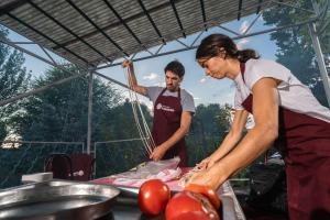 un hombre y una mujer preparando comida en una parrilla en ESENIN 1 Hostel & Bar, en Karakol