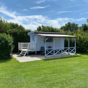 ein kleiner Schuppen mit einer Veranda im Gras in der Unterkunft Shepherds hut (Pipowagen) in Oostvoorne