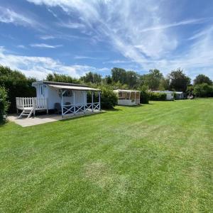 un grand jardin avec un hangar et une pelouse dans l'établissement Shepherds hut (Pipowagen), à Oostvoorne