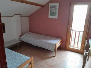 a small bedroom with two beds and a window at Refuge de Roncharel in Annot