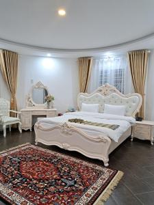 a bedroom with a large white bed and a rug at LẠC DƯƠNG TIÊN CẢNH (BULGALOW) in Xuan An