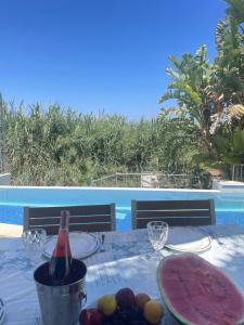 una mesa con una botella de vino y un plato de fruta en Gold Sand Villa, en Protaras