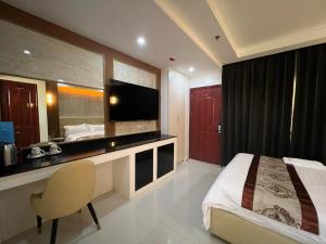 a bedroom with a bed and a desk with a television at HOTEL ERICH in Tuguegarao City