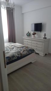 een slaapkamer met een bed en een dressoir met een televisie bij Campus in Constanţa