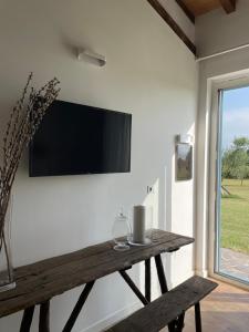 a living room with a wooden table and a tv on the wall at THE RANCH Apartment 3 Capalbio in Pescia Romana