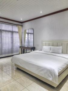 a bedroom with a large white bed and a table at In Villa Garden Resort in Batu
