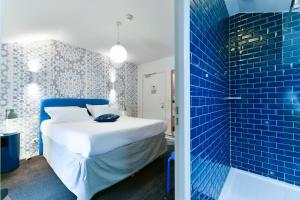 sypialnia z łóżkiem i niebieską ścianą wyłożoną kafelkami w obiekcie Hôtel Argia w mieście Hasparren