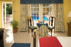 um quarto com uma cama, uma mesa e cadeiras em Polkerris Bed & Breakfast em Montego Bay