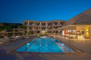 a pool in front of a hotel at night at Remezzo Studios & Apartments in Amoudi