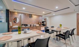 a dining room with tables and chairs and a kitchen at Treebo Trend MVP Grand in Visakhapatnam