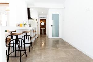 a kitchen with white walls and bar stools at Apt. con balcón y vistas a la playa Alguer in L'Ametlla de Mar