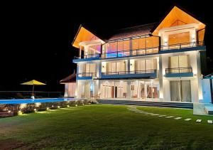 a large building with a lawn in front of it at night at Serenemo Eco Resort in Pundaluoya