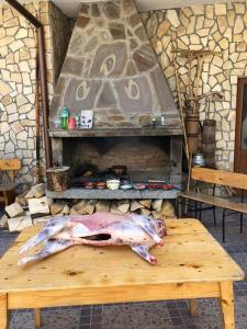 un cerdo grande tirado en una mesa de madera frente a una chimenea en Къща за гости Камината en Trigrad