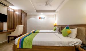 a hotel room with two beds and a desk at Treebo Trend PL Grand Vishakapatnam in Visakhapatnam