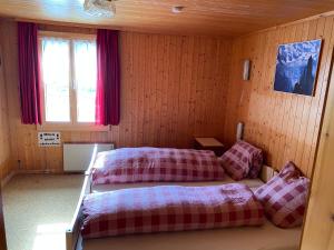 1 dormitorio con 2 camas en una habitación con paredes de madera en Rigi-Burggeist Alpine Guesthouse en Gersau