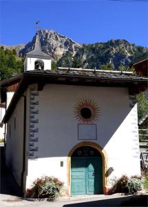 a white church with a green door and a clock at Chalet familial de village en Savoie in Peisey-Nancroix