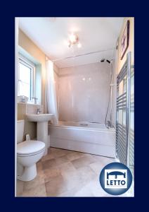 a bathroom with a toilet and a tub and a sink at Letto Serviced Accommodation Peterborough - Davis House - PE7 - FREE Parking in Peterborough