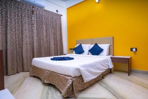 a bedroom with a large bed with a yellow wall at SS Mystic Apartotel in Bangalore