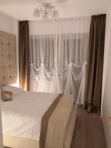 a bedroom with a bed with white curtains and a chandelier at Apartament de lux white&red in Suceava