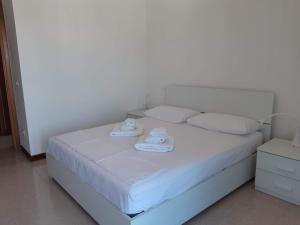 a white bed with two towels on top of it at Villa a schiera con uso piscina in Aprilia Marittima +19 photos