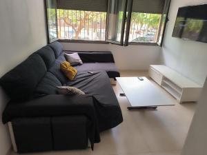 a living room with a black couch and a table at turisblo apartamento 2 in Benicarló