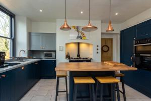 a kitchen with blue cabinets and a wooden island with stools at St Marks Stays in Sedbergh