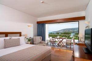 1 Schlafzimmer mit einem Bett und einem Balkon mit einem Tisch in der Unterkunft Elounda Beach Hotel & Villas, a Member of the Leading Hotels of the World in Elounda