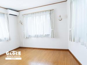 um quarto vazio com uma janela e um piso de madeira em GLOCE 逗子ビーチハウス l ZUSHI BEACH HOUSE em Zushi