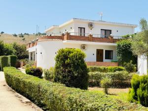 a white house with a hedge in front of it at Vila Demiraj Ksamil Sarande in Ksamil