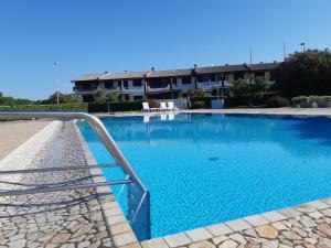a blue swimming pool with a metal rail next to a building at Villa a schiera con uso piscina in Aprilia Marittima