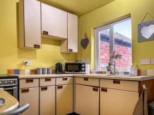 a kitchen with yellow walls and white cabinets and a window at Regent House in Leek
