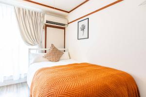 a bedroom with a bed with an orange blanket at エステラス大阪ウエスト103 in Osaka