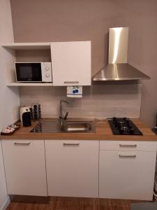 a kitchen with white cabinets and a sink and a microwave at Appartamento Regina in Borso del Grappa