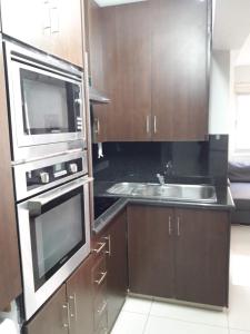 a kitchen with wooden cabinets and a sink and a microwave at A MODERN APARTMENT FOR YOU in Nicosia