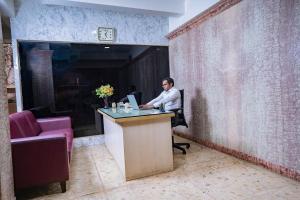 SS Mystic Apartotel في بانغالور: رجل يجلس في مكتب مع الكمبيوتر المحمول