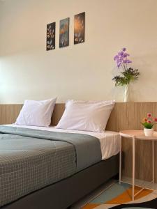 łóżko z białą pościelą i wazą z fioletowymi kwiatami w obiekcie myRumah Imperio Home , Alor Setar 3BR with Sky Infinity Pool w mieście Alor Setar
