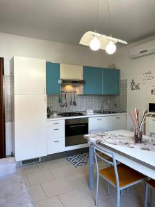 a kitchen with white cabinets and a table with chairs at Maisonette cibeno in Carpi