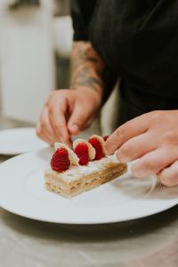 une personne mangeant un morceau de gâteau avec des baies sur une assiette dans l'établissement Grand Tonic Hotel & SPA NUXE, à Biarritz