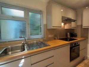 een keuken met witte kasten, een wastafel en een raam bij Treetop Cottage at Countisbury Lodge in Lynmouth