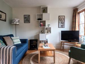 een woonkamer met een blauwe bank en een tafel bij Treetop Cottage at Countisbury Lodge in Lynmouth