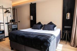 a bedroom with a large bed with black sheets and pillows at Palace Hotel Zandvoort in Zandvoort