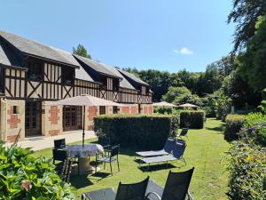 une maison avec des chaises et un parasol dans la cour dans l'établissement Le manège Gite L'Eglise, à Sainte-Marie-au-Bosc