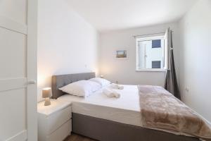 a bedroom with a bed with white sheets and a window at Sea view by Moro in Malinska