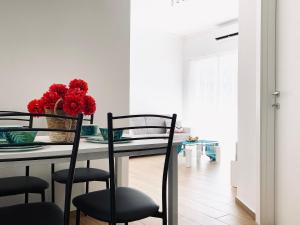 a dining room table with chairs and a vase of red flowers at Miami Apartments in St. Julianʼs