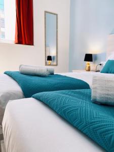 a row of four beds with blue and white sheets at Miami Apartments in St. Julianʼs