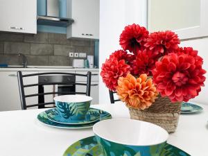 a table with two cups and a vase with flowers at Miami Apartments in St. Julianʼs