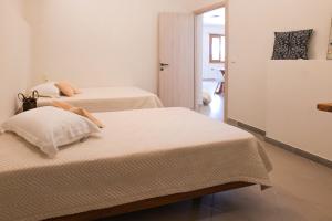 zwei Betten in einem Zimmer mit weißen Wänden in der Unterkunft Mirabilia deluxe apartment in Arillas