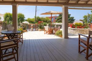 eine Terrasse mit Tisch, Stühlen und Sonnenschirm in der Unterkunft Mirabilia deluxe apartment in Arillas