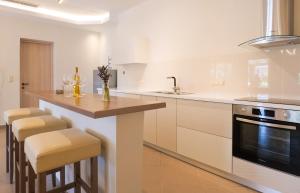 eine Küche mit weißen Schränken und einer Theke mit Stühlen in der Unterkunft Mirabilia deluxe apartment in Arillas + 6 Fotos