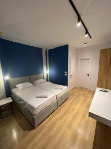 1 dormitorio con 1 cama con pared azul en Capital Suites Center, en Tirana